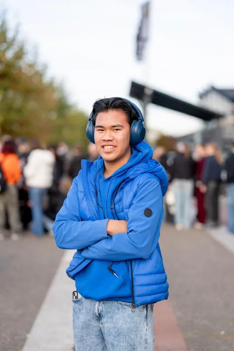 Portret van Tjinnakon met koptelefoon, publiek wazig op de achtergrond.